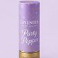 A product lineup graphic showing lavender and silver party accessories on a light lavender background, including a gold and lavender crown, lavender snow spray cans, a silver tiara, a lavender party popper, a lavender spiral candle, and two silver sparkles.